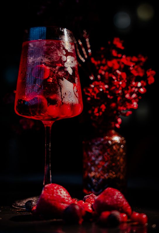 Tiefroter Beeren-Spritz im Weinglas mit Eis und frischen Beeren